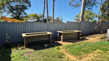 Two raised timber and Colorbond garden beds along a backyard fence