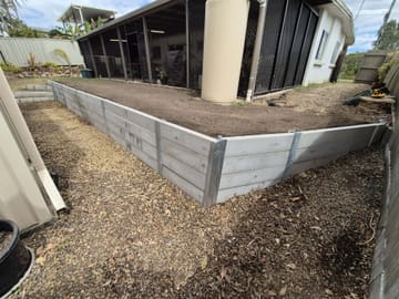 Concrete sleeper retaining wall with galvanised steel posts beside a house