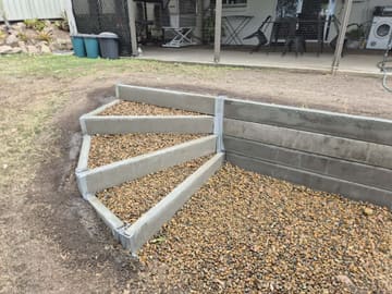 Custom curved concrete sleeper steps with gravel built into a retaining wall in Holmview