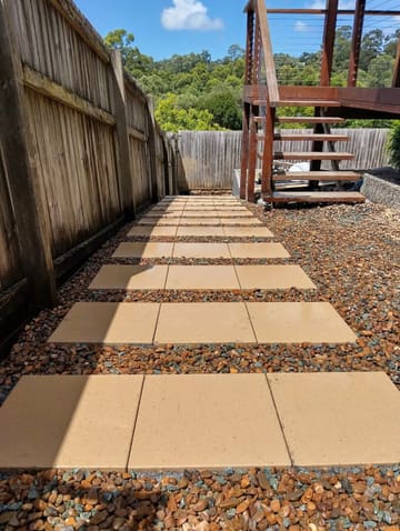 Sandstone-coloured pavers set in river pebbles beside timber stairs