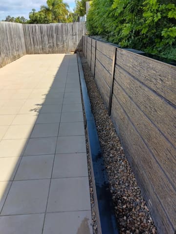 New paved courtyard with a Moreton sleeper garden edge and gravel strip beside a retaining wall
