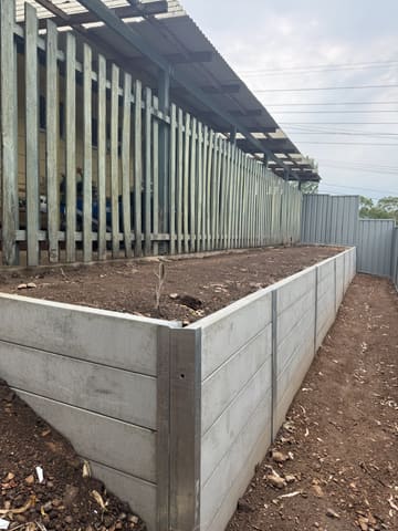 Raised concrete sleeper garden wall beside a Colorbond fence