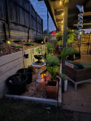 Courtyard garden with gravel and pots in front of a concrete sleeper retaining wall at dusk