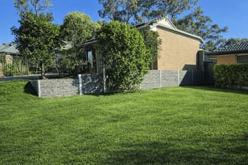 Blakeview stacked-stone concrete sleeper garden wall across the front of a brick home