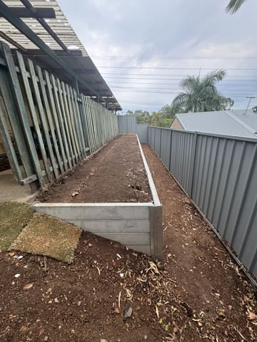 Long concrete sleeper garden bed along a fence